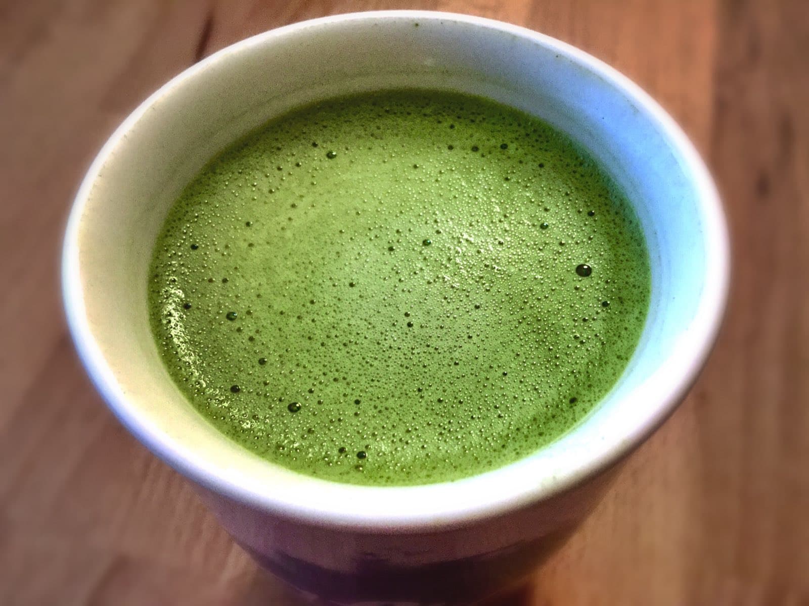 A matcha latte in a ceramic cup on a wooden surface, shot from above