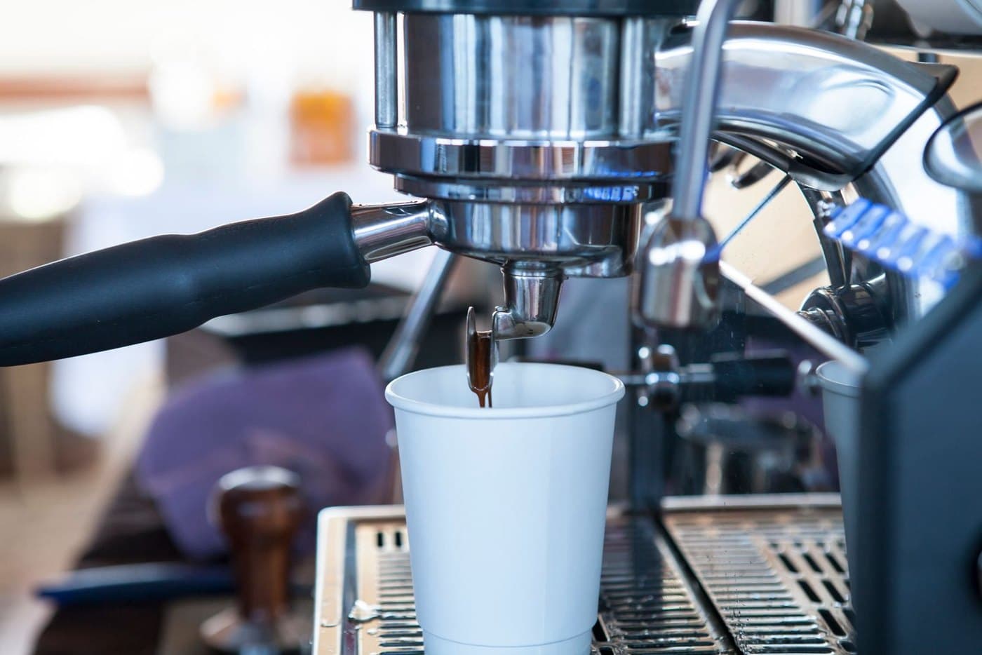 Máy pha espresso đang chiết xuất cà phê xuống ly; nước cứng là nguyên nhân gây cặn vôi trong máy